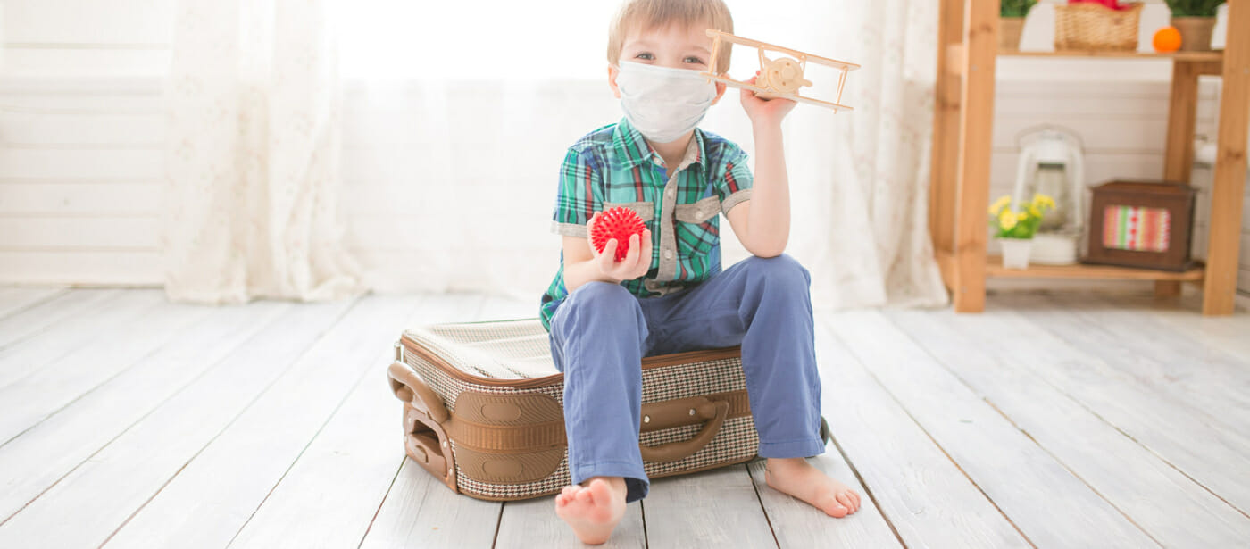 Little cute kid boy in quarantine at home dreams of traveling.