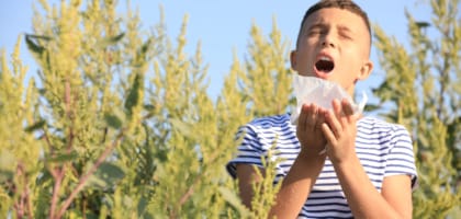 A young boy sneezes due to ragweed pollen, a major fall allergen in Corpus Christi.