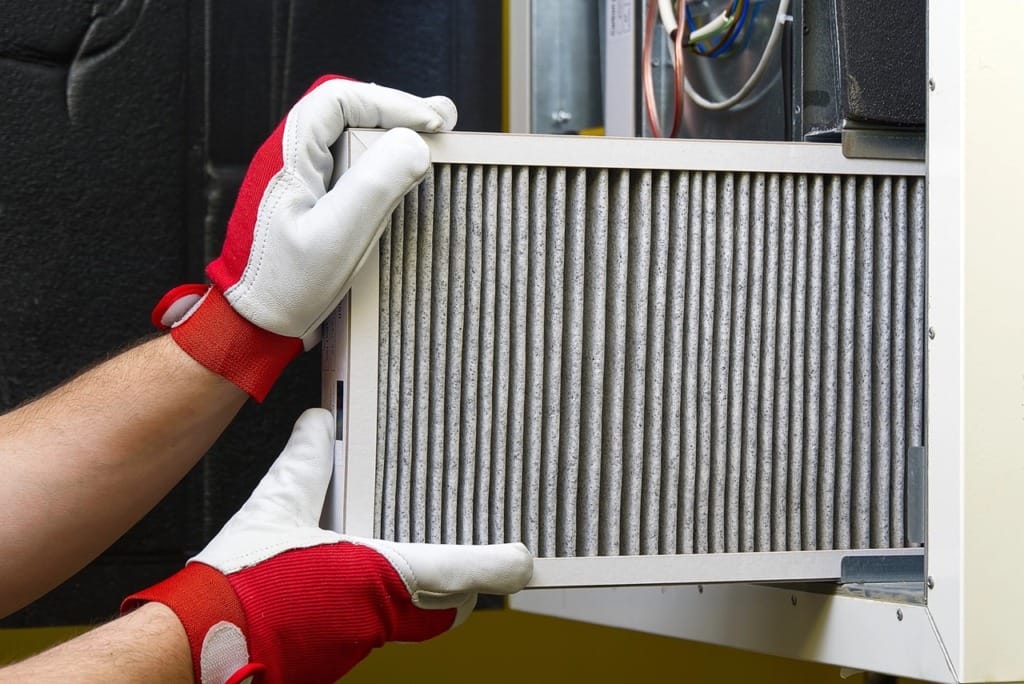 Person changing HVAC air filter to reduce indoor allergens