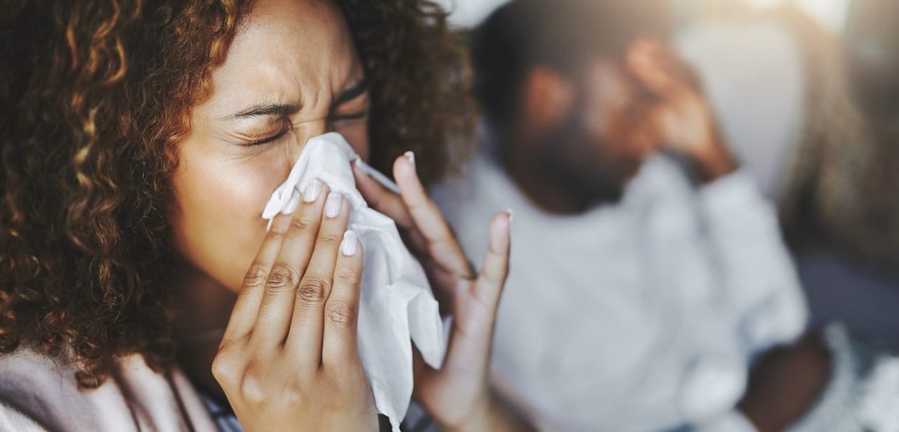 Person sneezing indoors with winter allergy symptoms